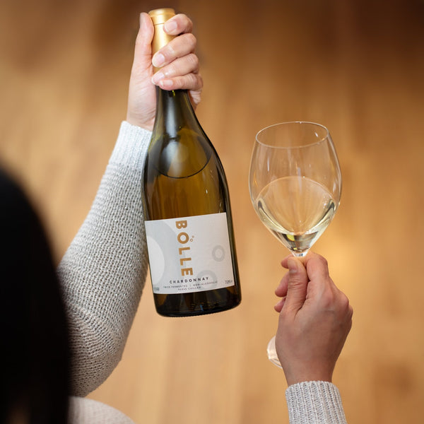 Person holding BOLLE Chardonnay non-alcoholic white wine bottle and glass